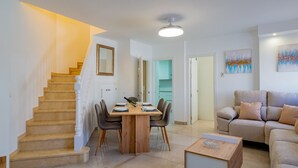 A modern living room with a staircase, a dining area, and a kitchen visible through an open door. - Cubo’s La Perla Town Center House / urban / air conditioning / free Wi-Fi (Alhaurín el Grande)
