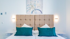 A double bed with two green pillows, a headboard with light fixtures, and a painting of a bicycle on the wall. - Cubo’s La Perla Town Center House / urban / air conditioning / free Wi-Fi (Alhaurín el Grande)