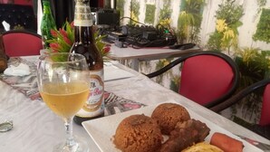 Ein Esstisch mit einer Bierflasche, einem Bierglas und einem Teller mit Reis, Fleisch und Gemüse.
