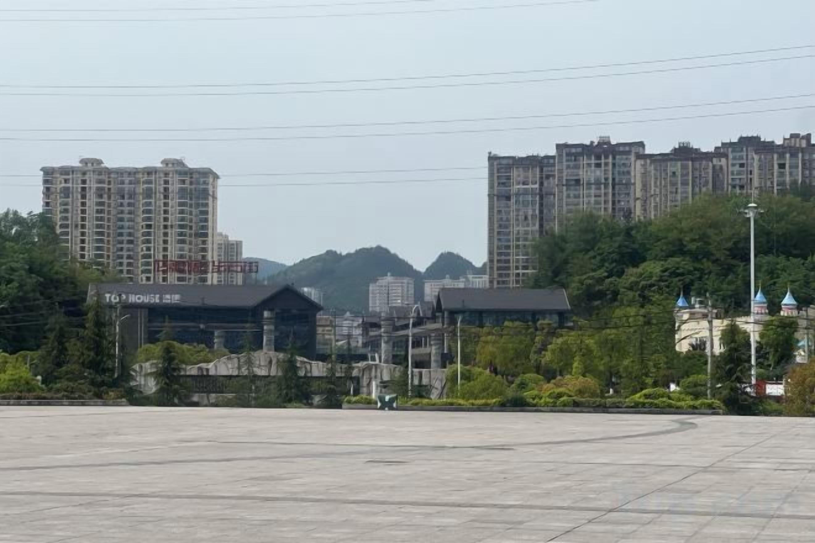 A large open plaza with buildings in the background, including a hotel with a sign.