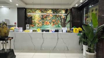 A reception area with a marble counter, a decorative wall mural, and a reception desk.