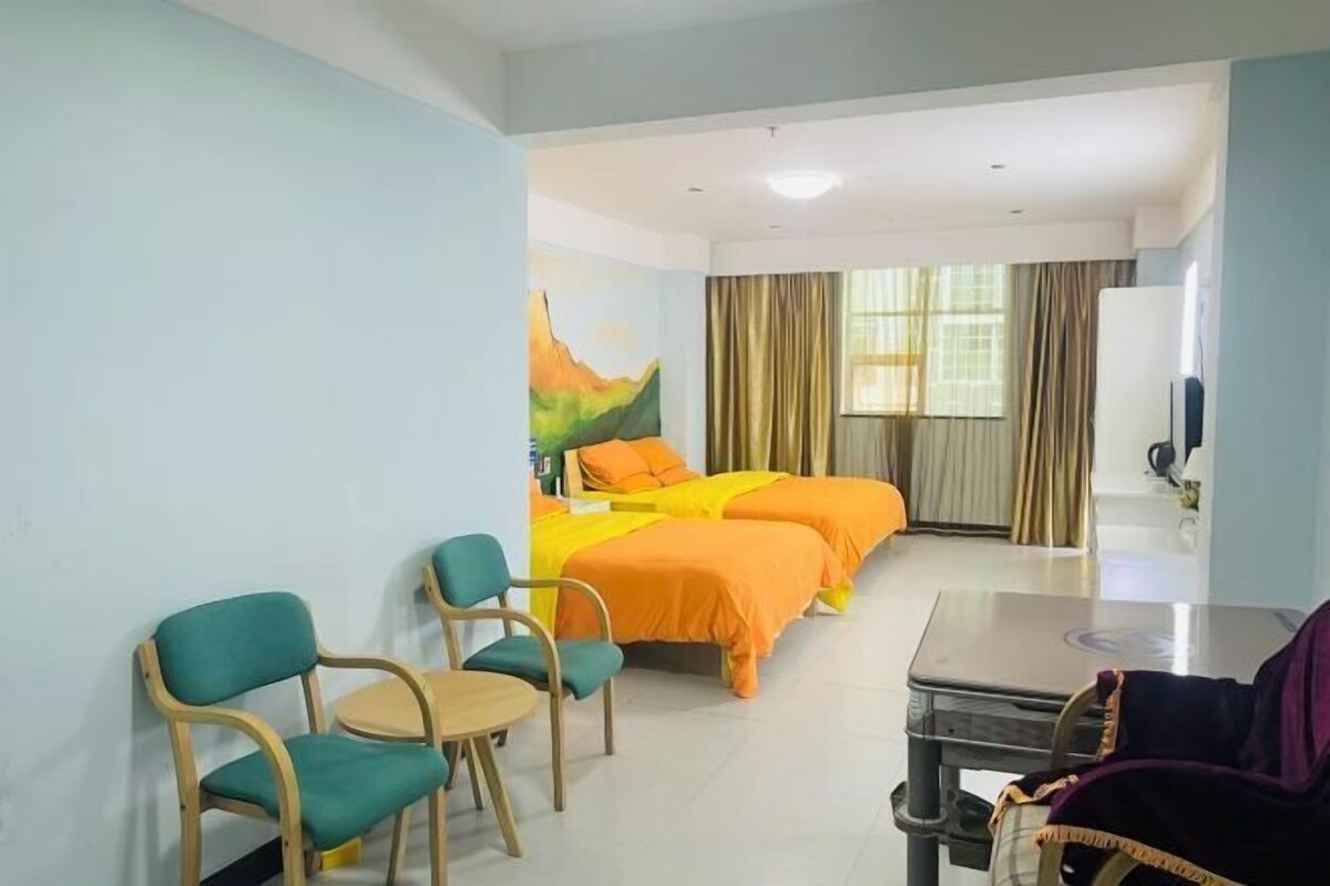 Een hotelkamer met twee bedden, een bureau, stoelen, een televisie en een schilderij aan de muur.