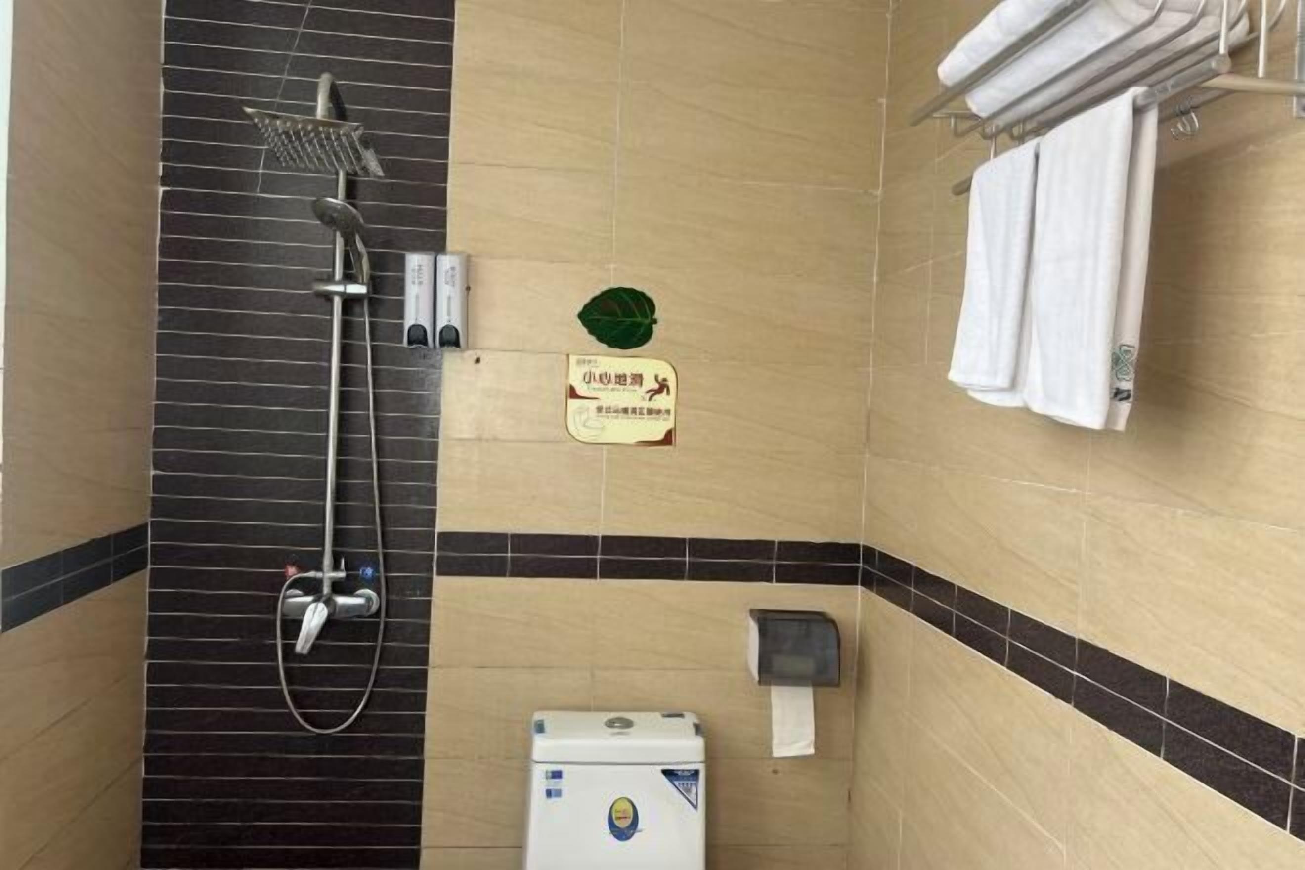 A bathroom with a shower, toilet, and towel rack.