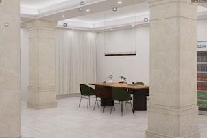 A modern dining area with a marble column, a long table, and green chairs.