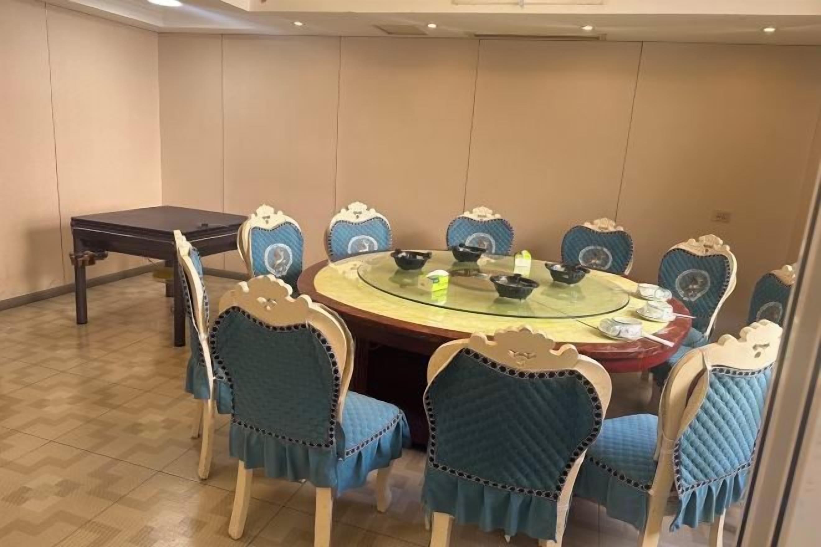 Une salle de conférence équipée d’une table ronde, de huit chaises à revêtement bleu et d’une table en bois foncé.