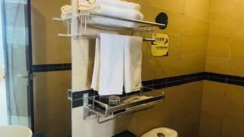A bathroom with a towel rack, a trash bin, and a sign on the wall.