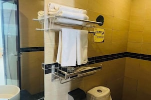 A bathroom with a towel rack, a trash bin, and a sign on the wall.