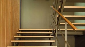 Un escalier en bois avec des rampes en métal et un mur vert.