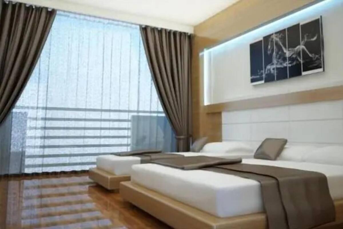 A modern hotel room with a large bed, a smaller bed, and a sofa. There is a window with curtains and a painting on the wall.
