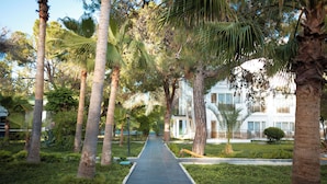 A pathway flanked by palm trees leading to a building with balconies. - Club Golf Hotel - All Inclusive (Manavgat)