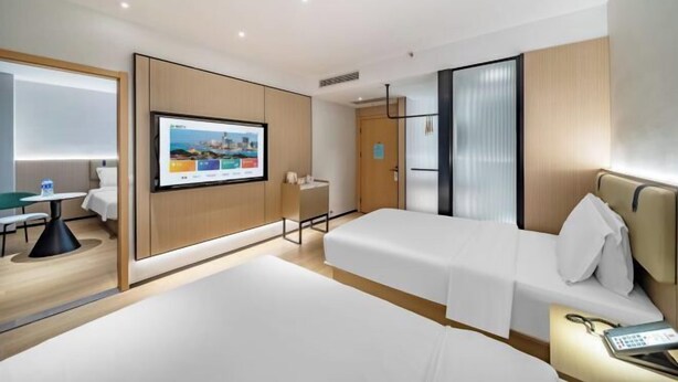 Hotellihuone, jossa on kaksi sänkyä, työpöytä, televisio ja kylpyhuone.