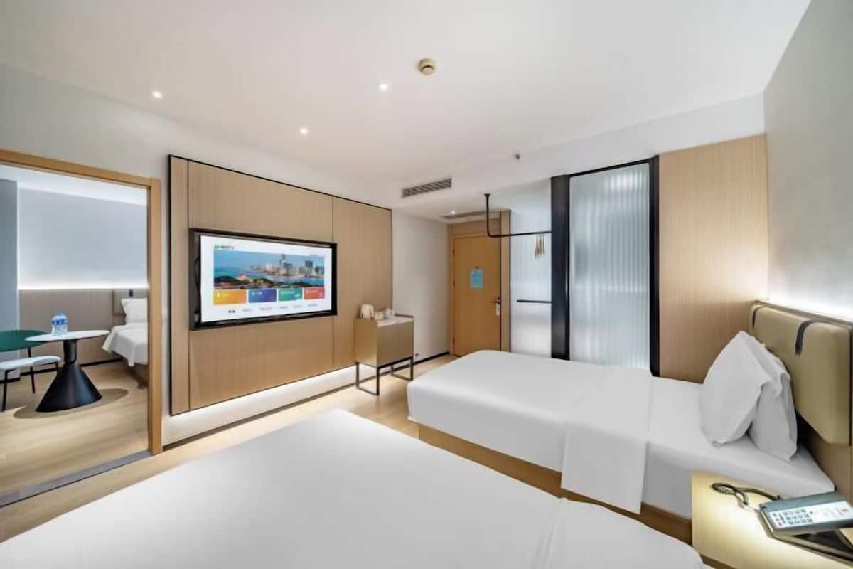 Een hotelkamer met twee bedden, een bureau, een televisie en een badkamer.