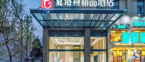 A hotel entrance with a modern design, featuring a glass canopy and a prominent signage.