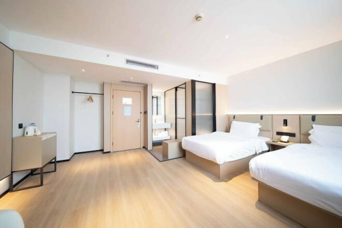 Een moderne hotelkamer met twee bedden, een bureau en een kledingkast.