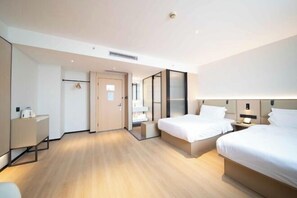 Et moderne hotelværelse med to senge, et skrivebord og et garderobeskab.