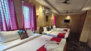 A hotel room with three beds, each with white bedding and red accents. There are pink curtains, an air conditioning unit, and a ceiling fan. - PV Tower - Auro Beach (Vanur)