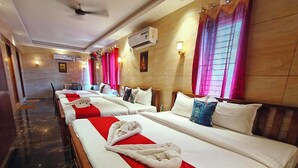 A hotel room with multiple beds, each with white linens and red accents, air conditioning units, and wall-mounted lamps. - PV Tower - Auro Beach (Vanur)