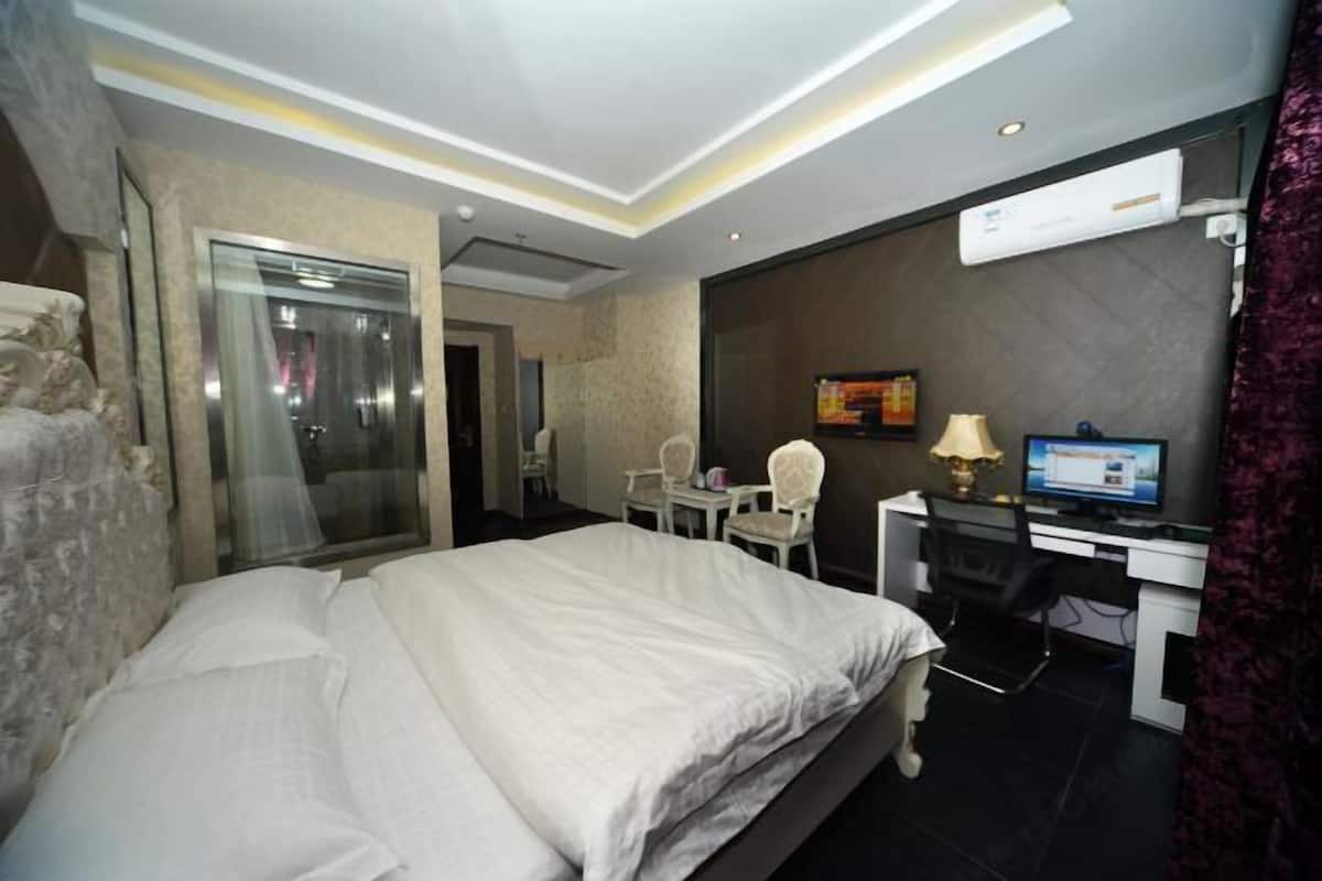 A hotel room with a bed, desk, chair, and a television.