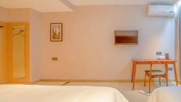 Een hotelkamer met twee bedden, een bureau, een stoel, een televisie en een airconditioning.