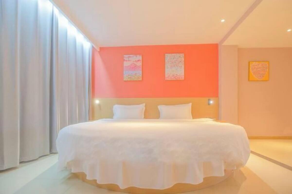 A hotel room with a bed, curtains, and artwork on the walls.