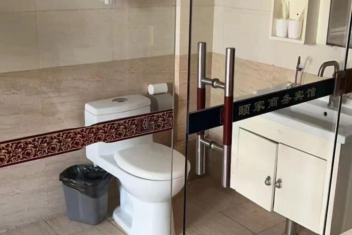 A bathroom with a toilet, a sink, and a trash bin.