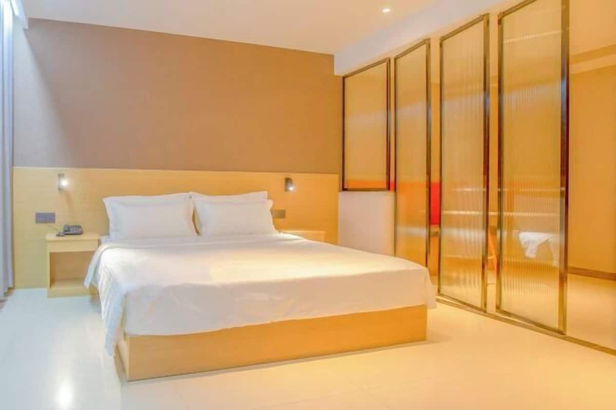 A modern hotel room with a large bed, a bedside table, and a wardrobe with sliding doors.