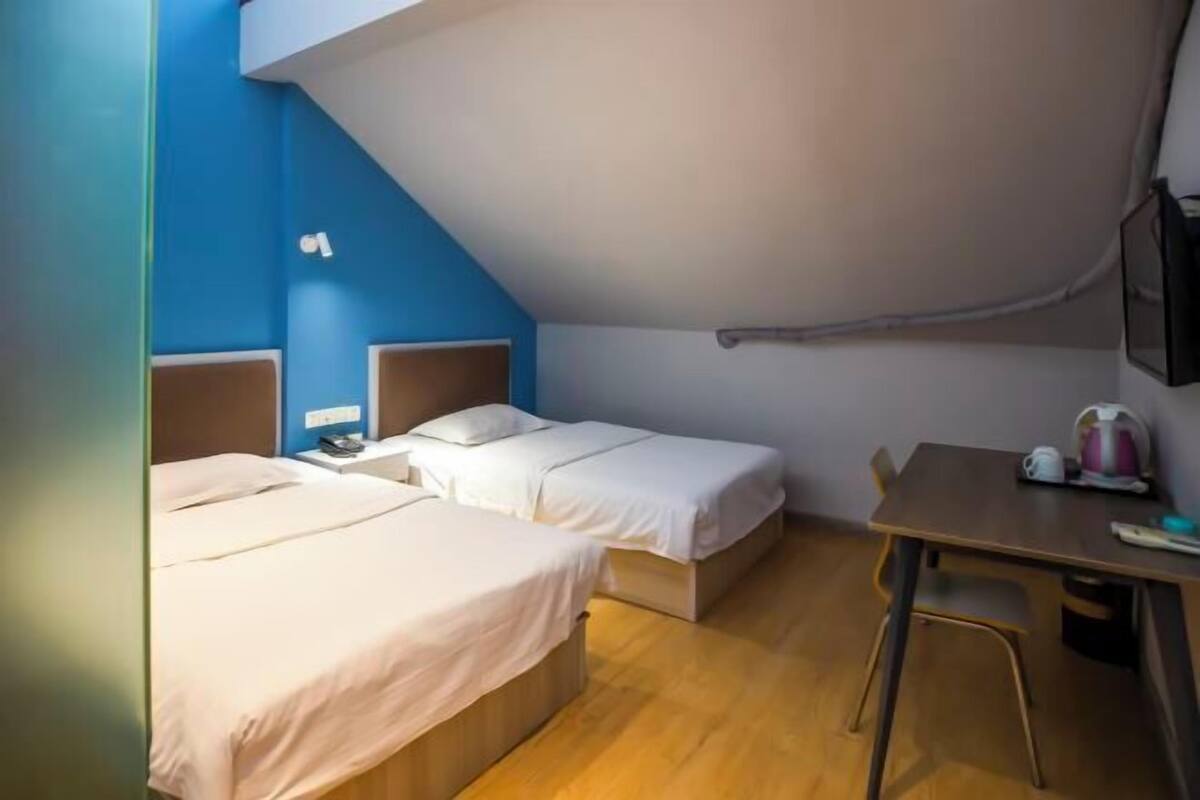 A room with two beds, a desk, and a chair.
