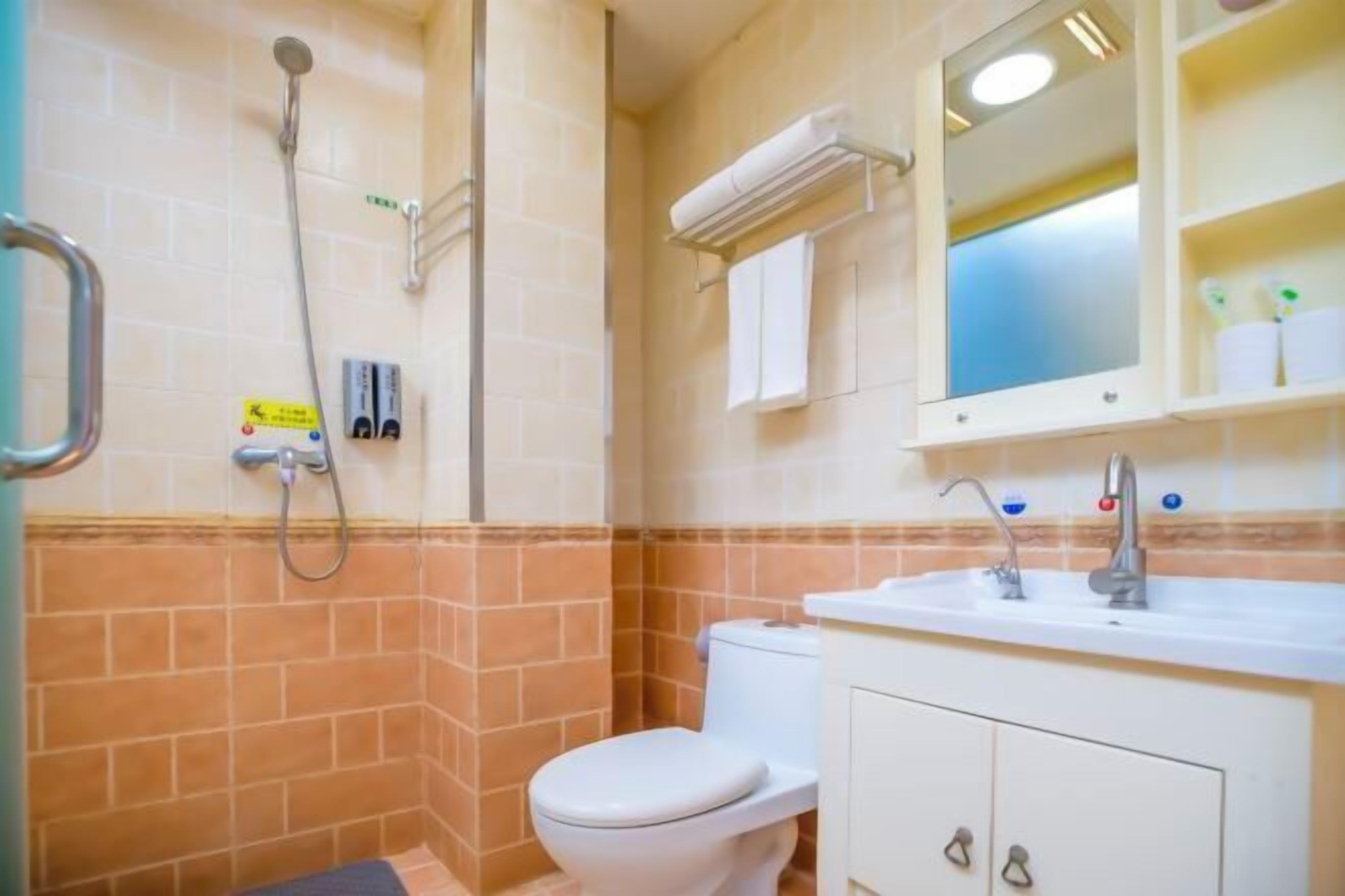 A bathroom with a shower, toilet, sink, and mirror.