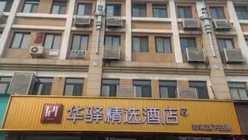 A hotel with multiple floors, air conditioning units on the exterior, and a prominent yellow sign with Chinese characters.