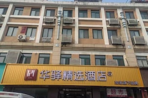 Un hotel de varios pisos, con unidades de aire acondicionado en el exterior y un letrero amarillo llamativo con caracteres chinos.