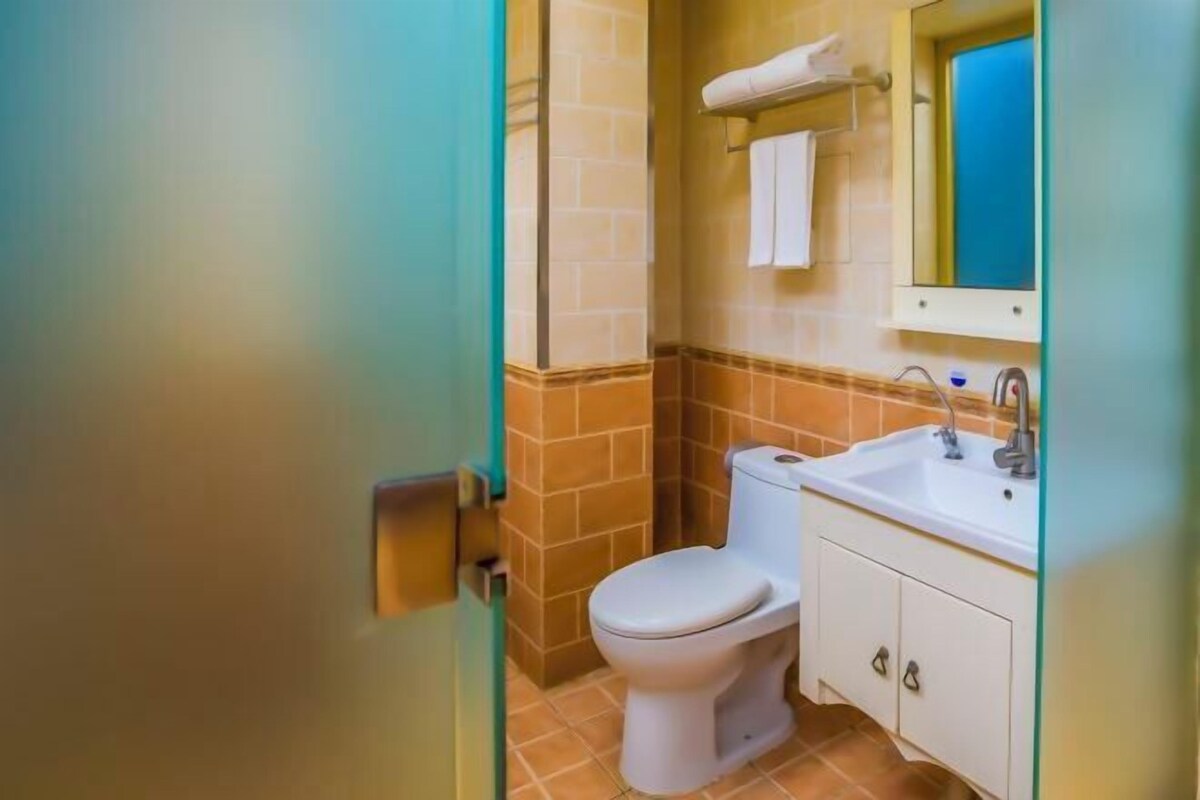 A bathroom with a toilet, sink, and mirror.