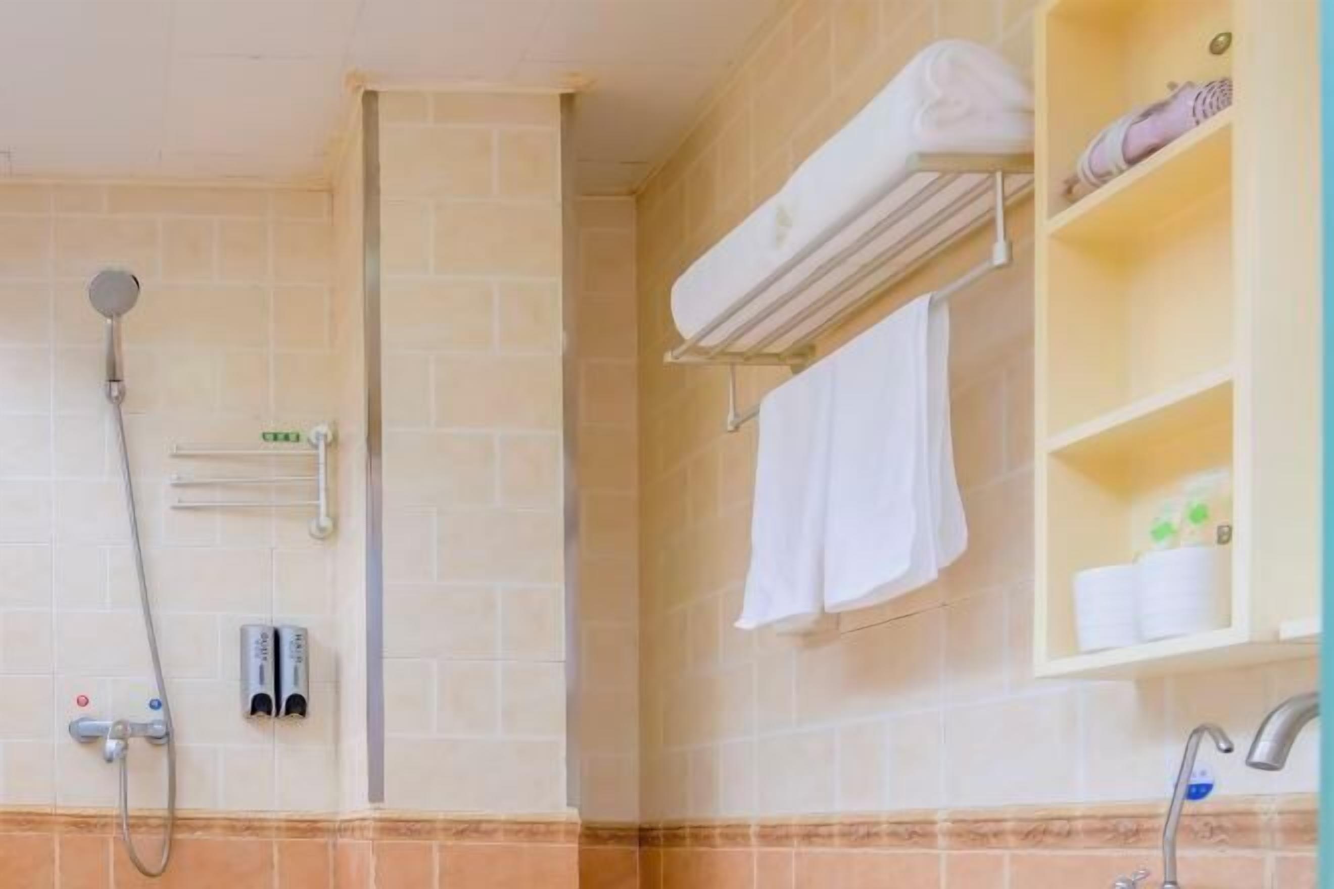 A bathroom with a shower, a towel rack, a shelf with toiletries, and a sink.