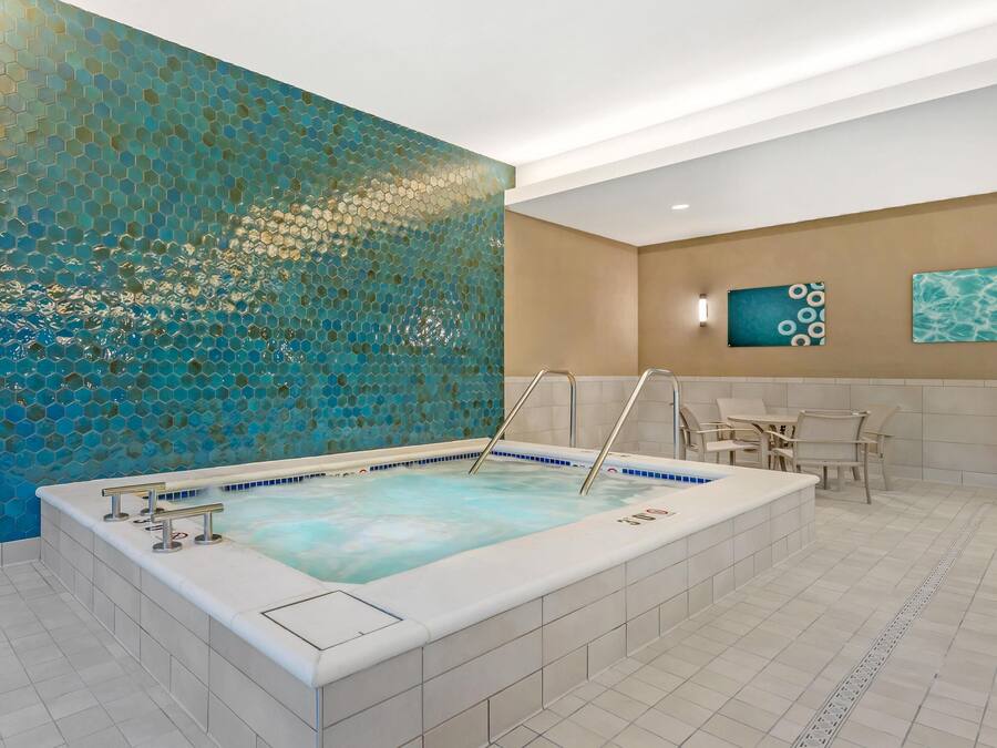 A spa area with a large hot tub, tiled floor, and a decorative wall with a honeycomb pattern.