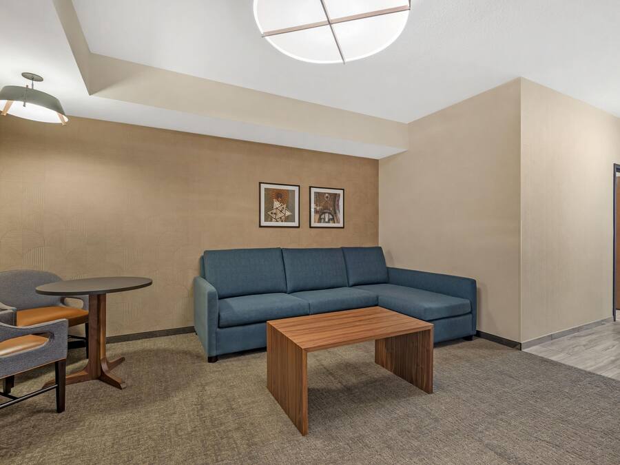 A modern room with a blue sofa, a small wooden table, and a round table with chairs. There are two framed pictures on the wall.
