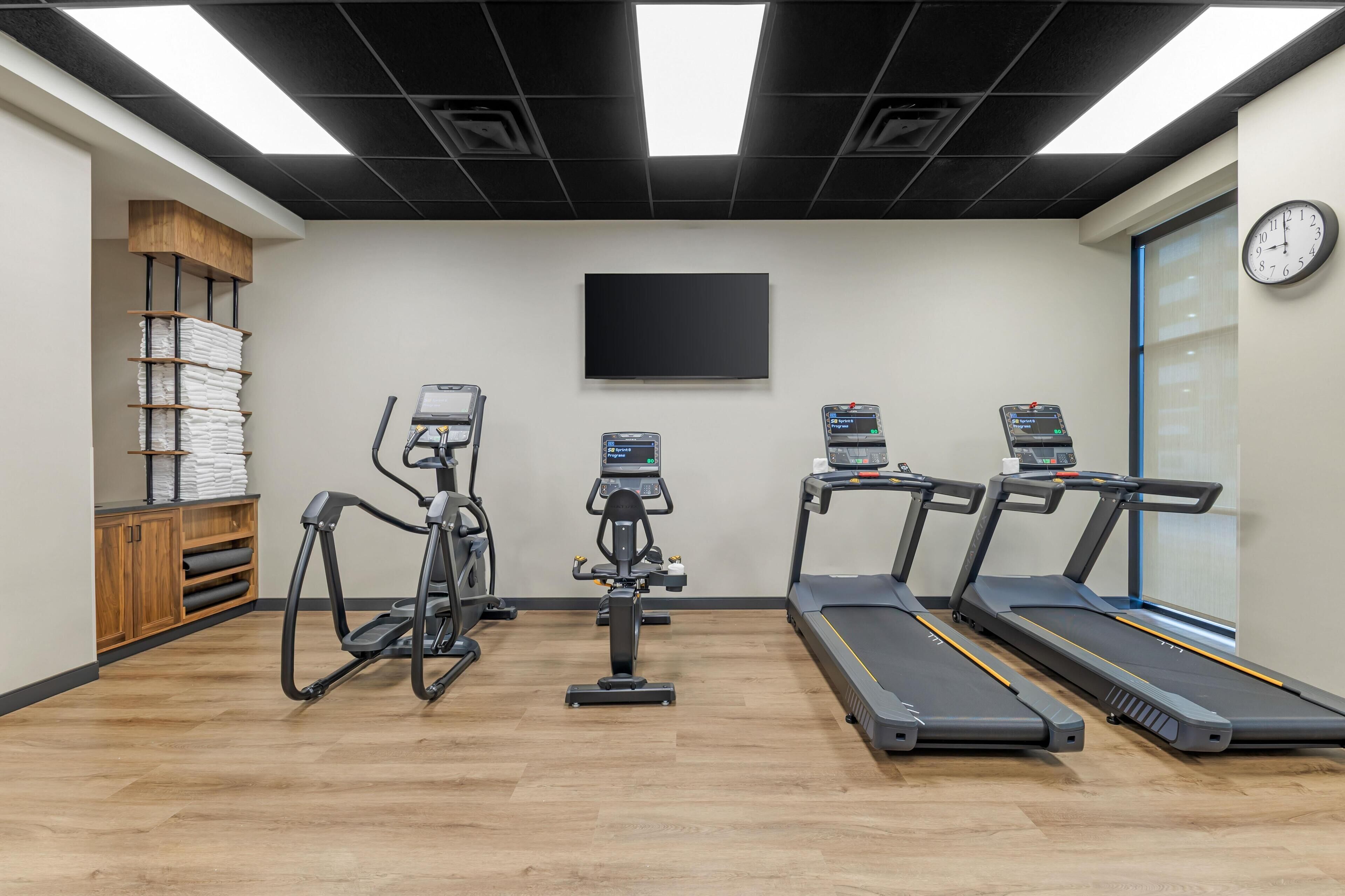 Une salle de sport équipée de tapis de course, d’un vélo elliptique et d’un vélo d’appartement.