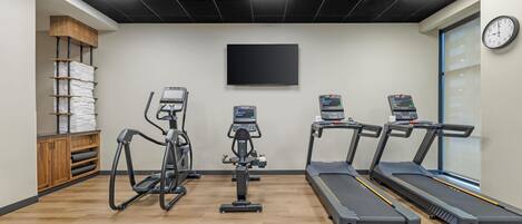 Ein Fitnessraum mit Laufbändern, Crosstrainern und einem stationären Fahrrad.