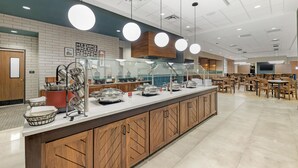 A buffet area with a counter, food containers, and seating in the background.