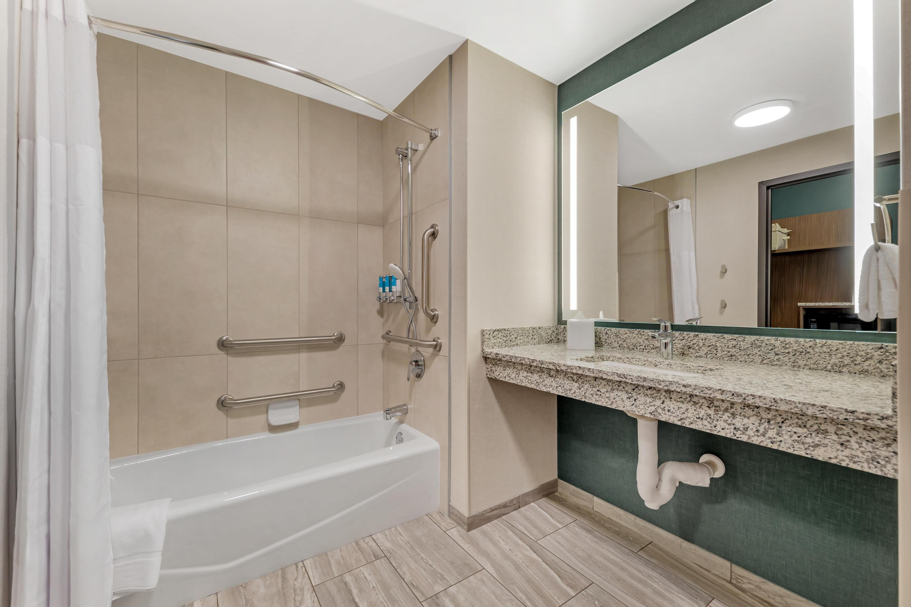 A modern bathroom with a bathtub, shower, and vanity with a mirror.