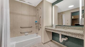 A modern bathroom with a bathtub, shower, and vanity with a mirror.