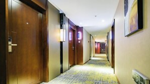 A hotel hallway with wooden doors, a patterned carpet, and a framed picture on the wall. - Vienna Classic Hotel (Kuanzhai Alley Luomashi Subway Station) (Chengdu)