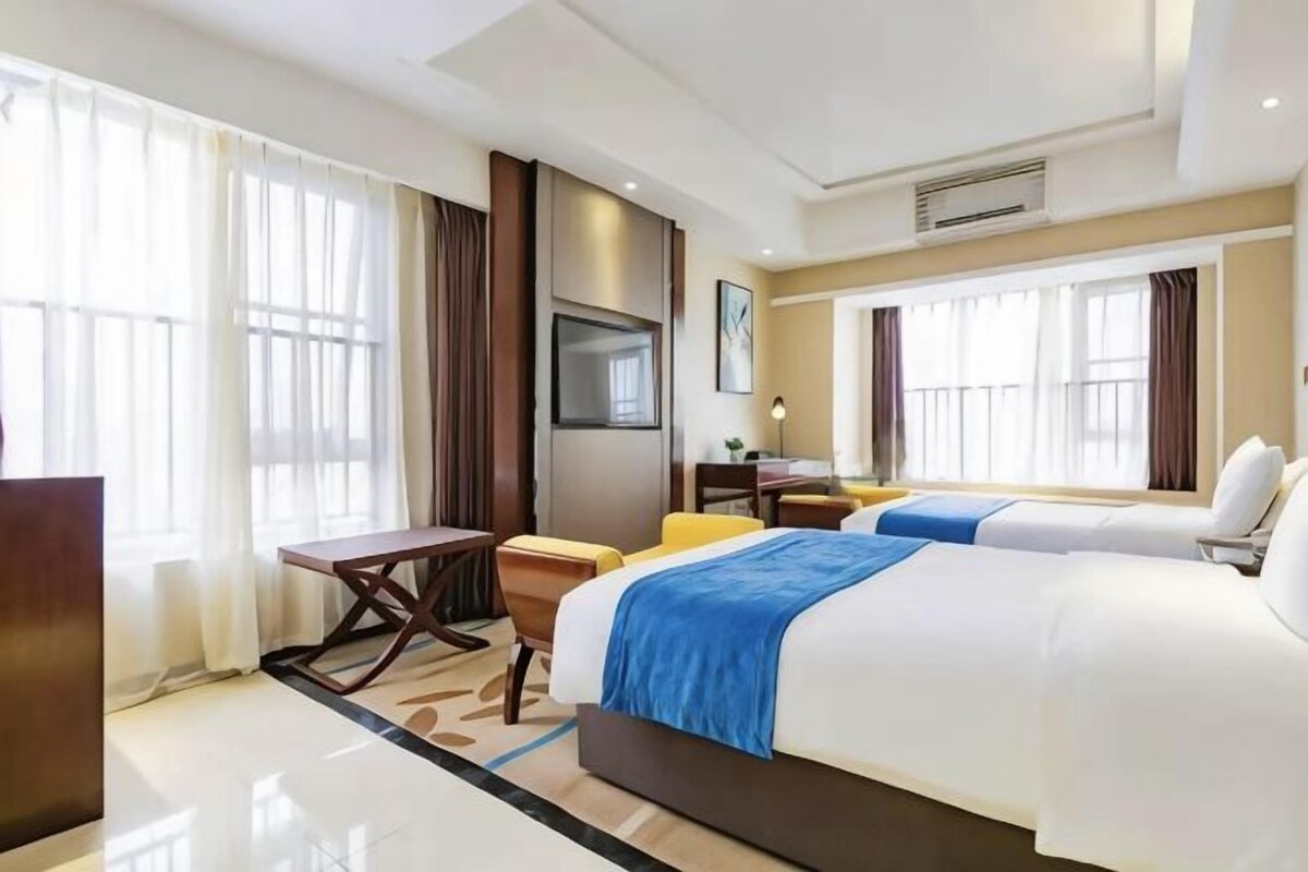 Una habitación de hotel con una cama grande, un escritorio, una silla y un televisor.