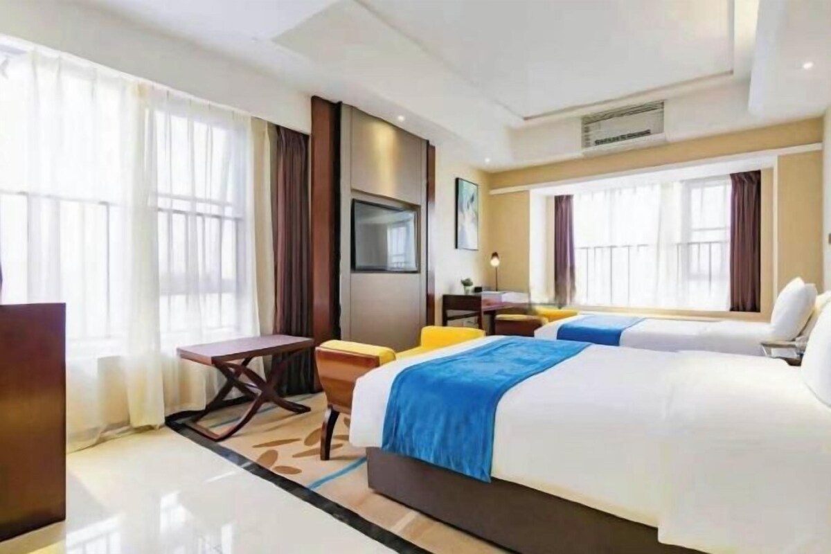 A hotel room with a large bed, a desk, a chair, and a television.