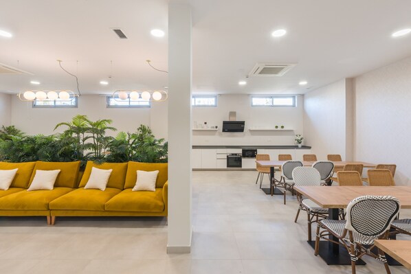 Una sala moderna con un sofá amarillo y un comedor con una mesa de madera y sillas de mimbre.