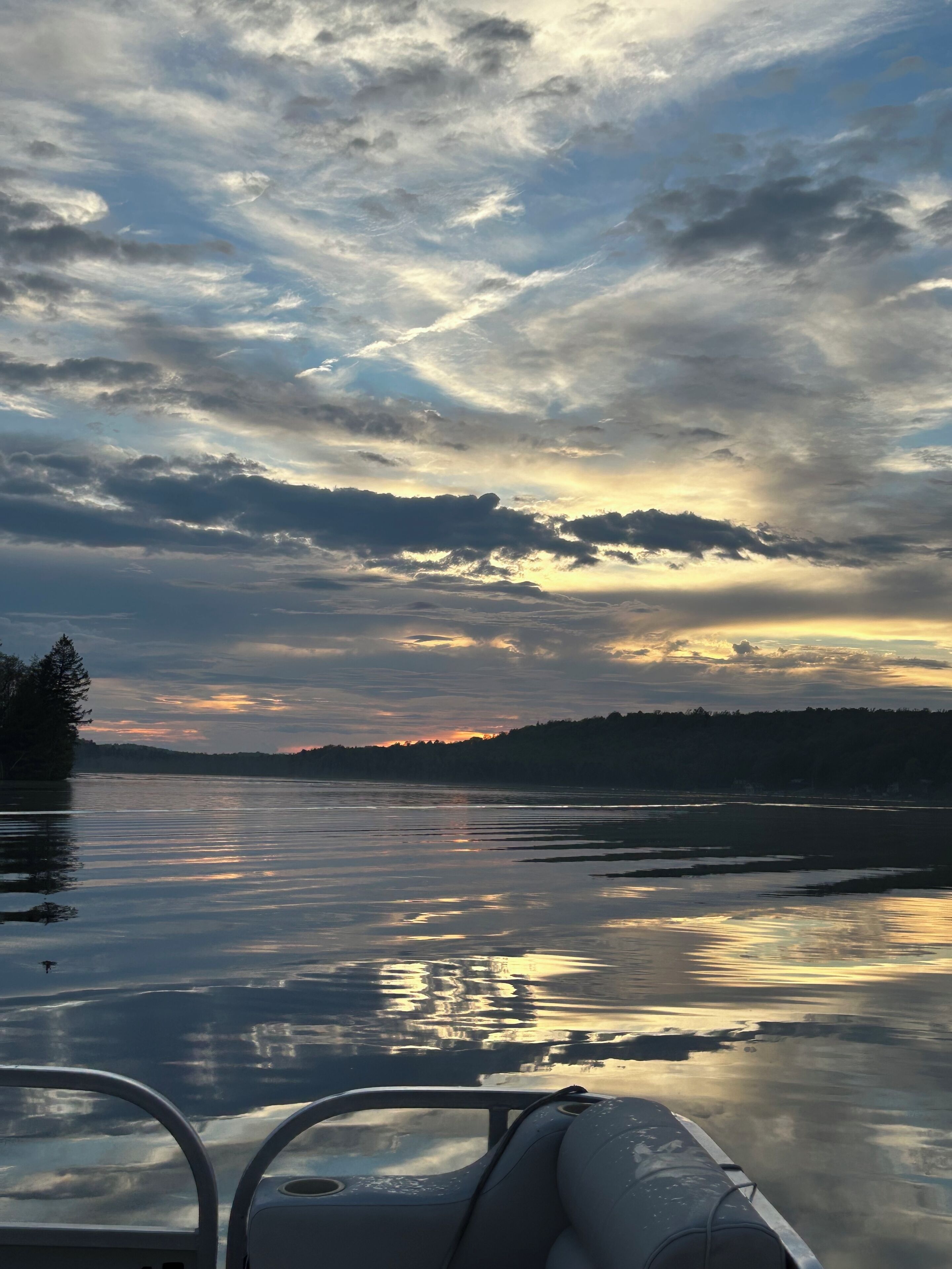 Un bote sobre aguas tranquilas, con vista a un cielo nublado y una costa distante.