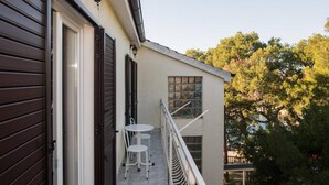 Un balcon avec une table et des chaises, une fenêtre et une porte.