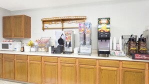 Un coin cuisine équipé d’armoires en bois, d’un four à micro-ondes, d’un appareil à gaufres, d’une machine à café et d’un réfrigérateur.