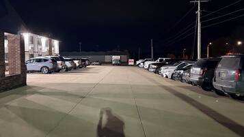 Een parkeerplaats met meerdere geparkeerde auto's, een gebouw met een bakstenen gevel en een heldere lucht.