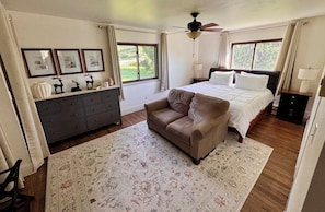 A bedroom with a bed, a dresser, a sofa, a ceiling fan, and two windows with curtains. - Sweeping Valley Sunsets \ 4BR, 3 Bath Retreat \ Minutes to Cornell and IC (Ithaca)