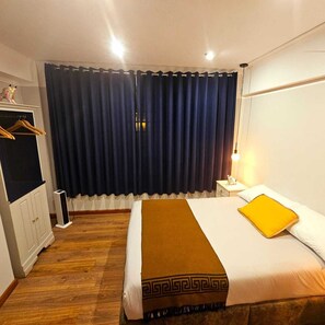 A hotel room with a bed, a nightstand, a wardrobe, and a window with curtains. - Margaritas (Cusco)
