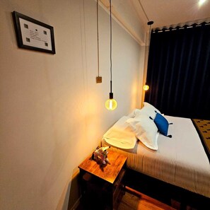 Een hotelkamer met een bed, een nachtkastje met een lamp en een ingelijst certificaat aan de muur.
